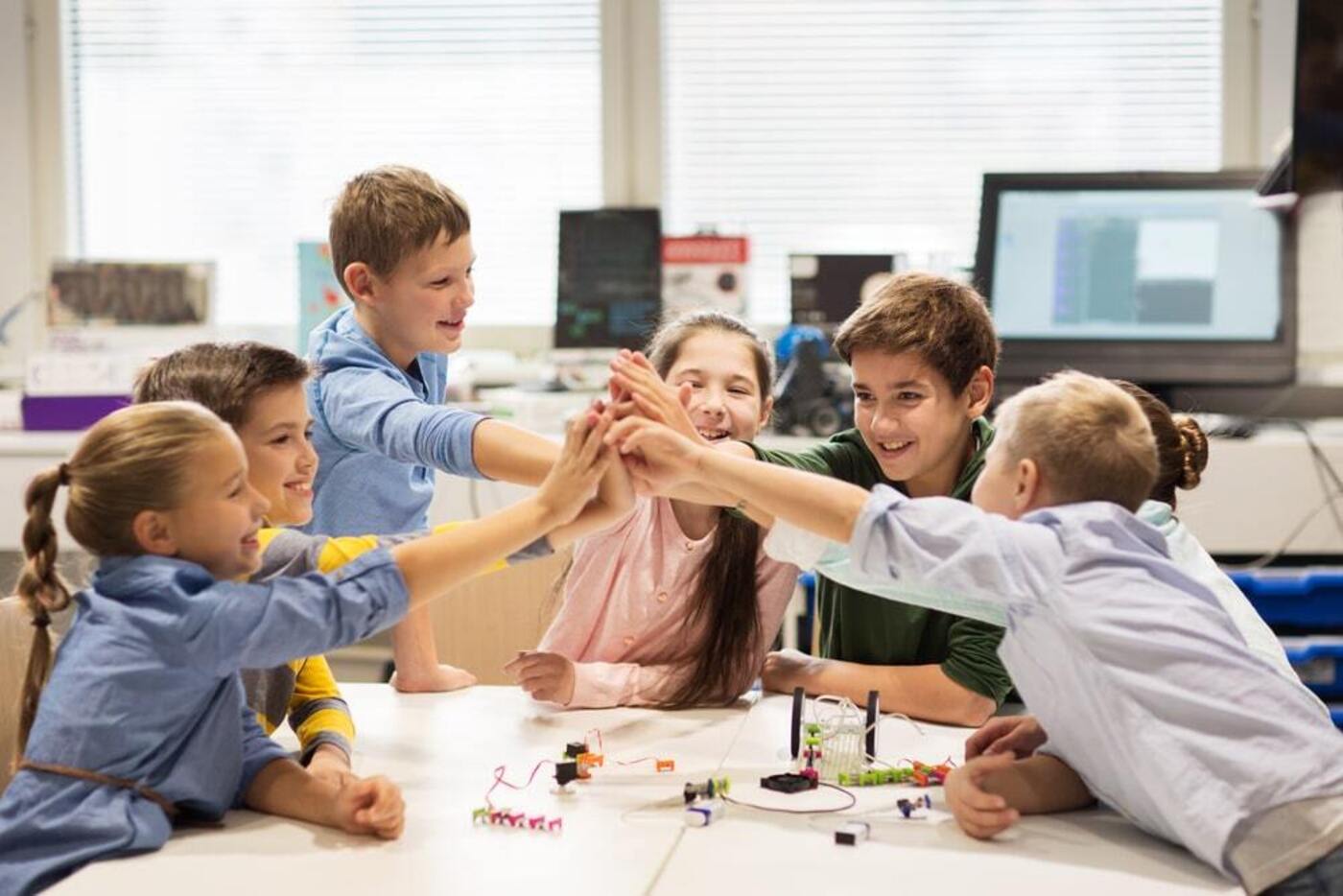 international schools Boston school children high five each other over robot project looking happy