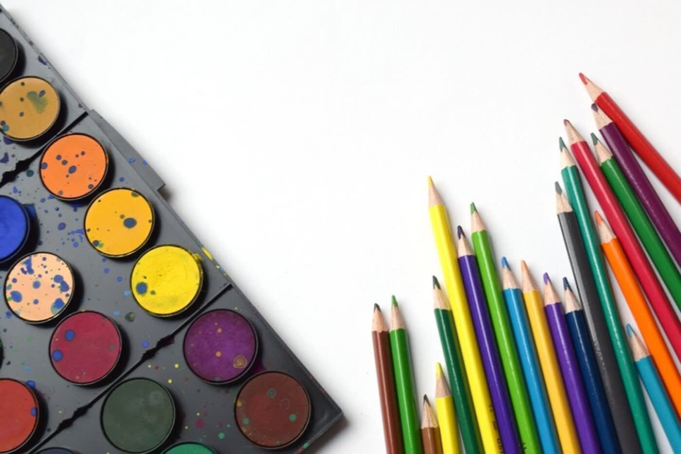 international schools in los angeles a paint set and colored pencil set laying on top of a white table