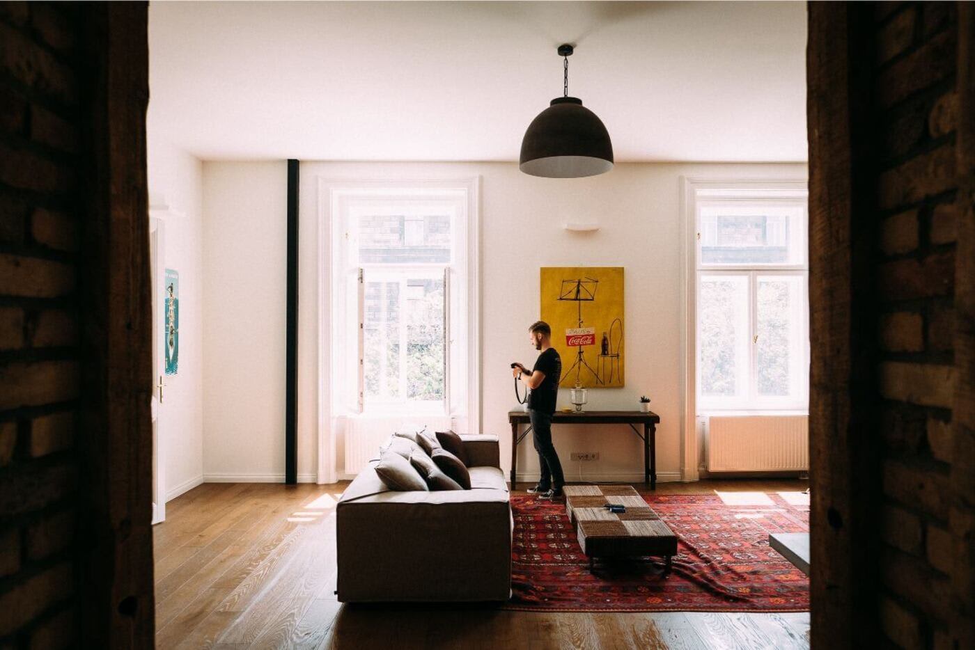 man standing in his apartment looking at something he is holding