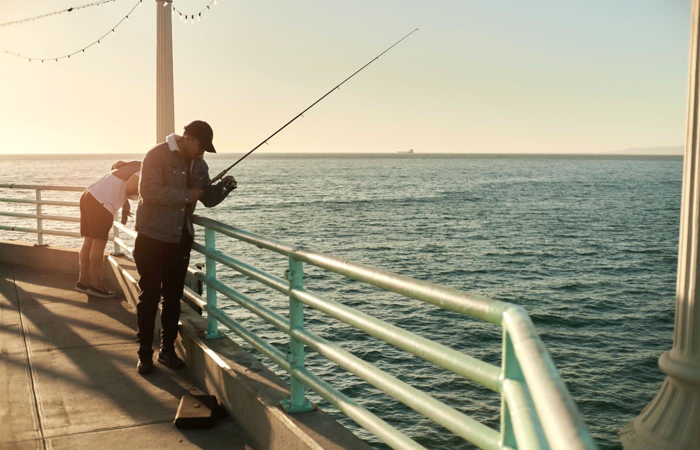 Two people fishing on a pier in manhattan beach los angeles.