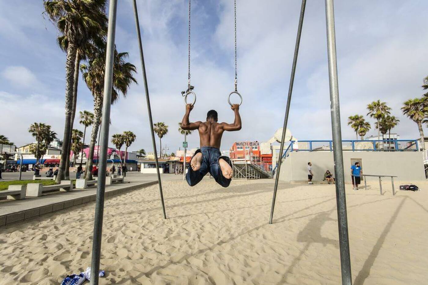man stretching on the rings doing pull ups on muscle beach in los angeles california
