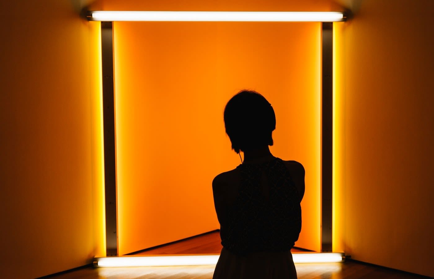 The silhouette of a person standing in front of a neon light art installation.