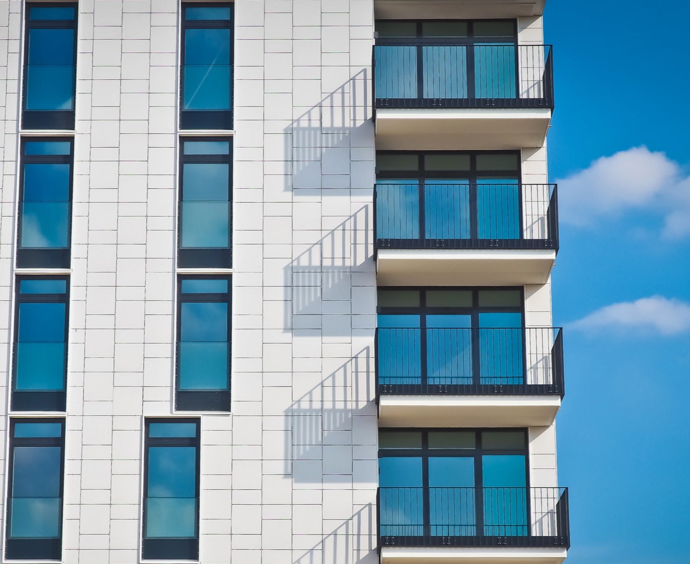 NYC apartment building against blue skies black framed windows