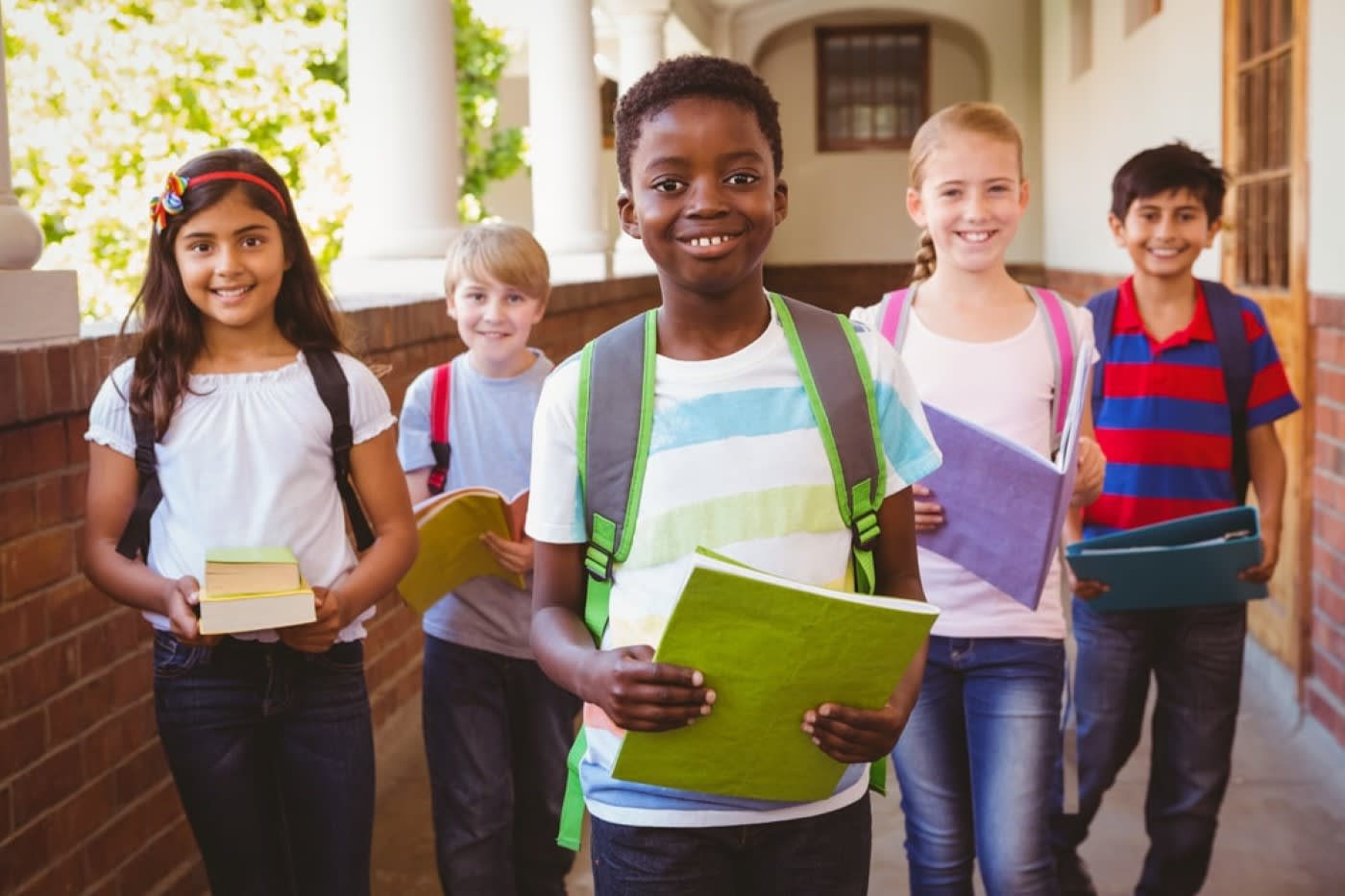 portrait of 5 school children smiling in school corridor