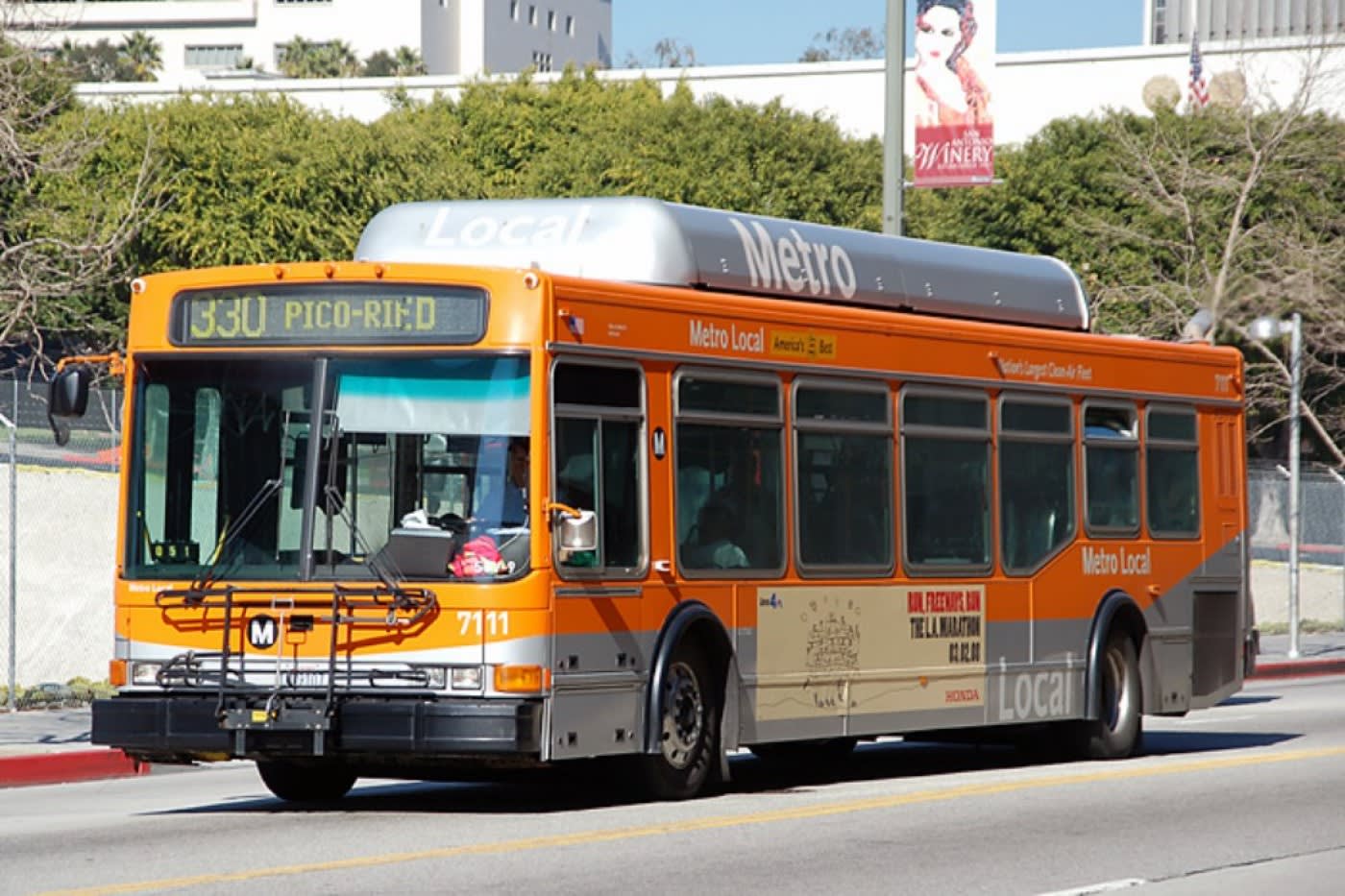 metrobus driving to next bus stop with building in the background