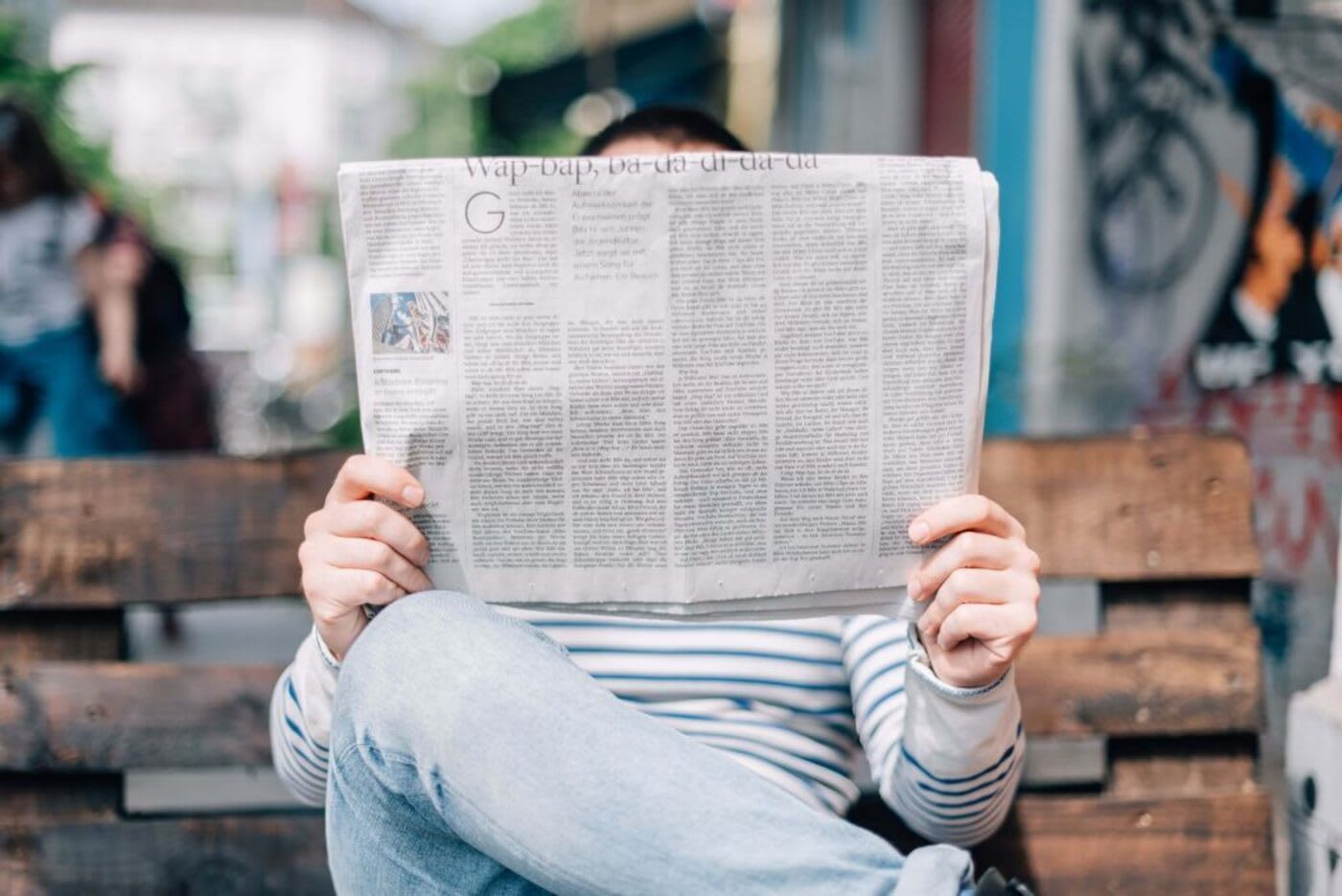 man sitting on a bench reading a newspaper