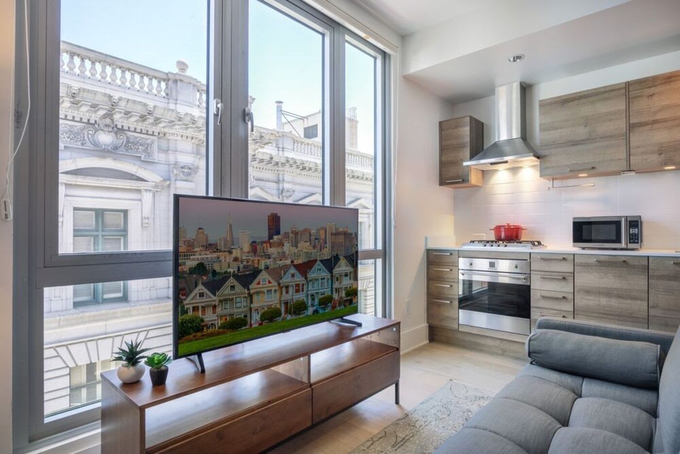 small living room with wooden kitchenette and a TV stand against the window