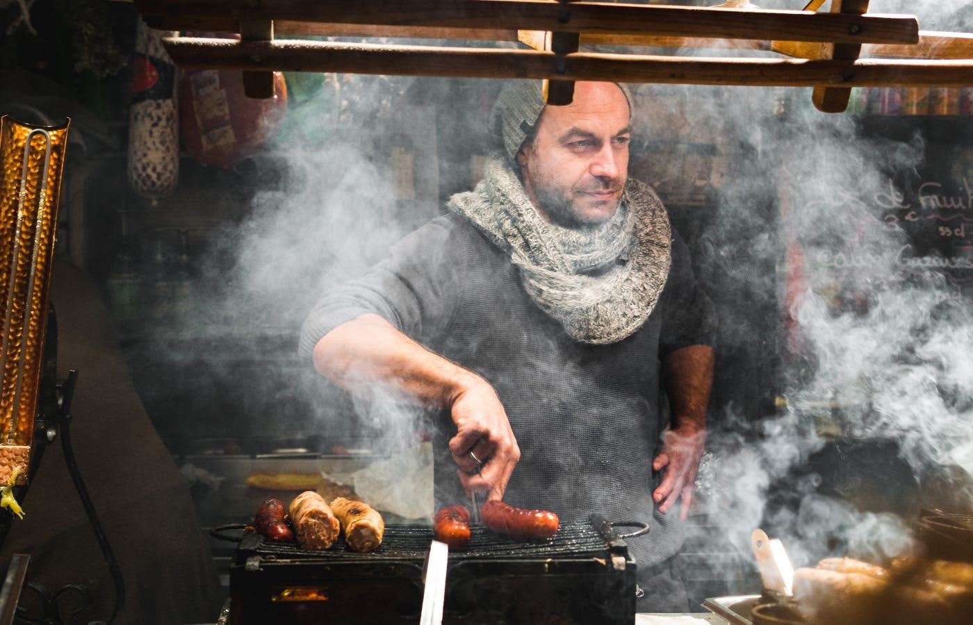 A street food vendor in his stall grilling sausages.