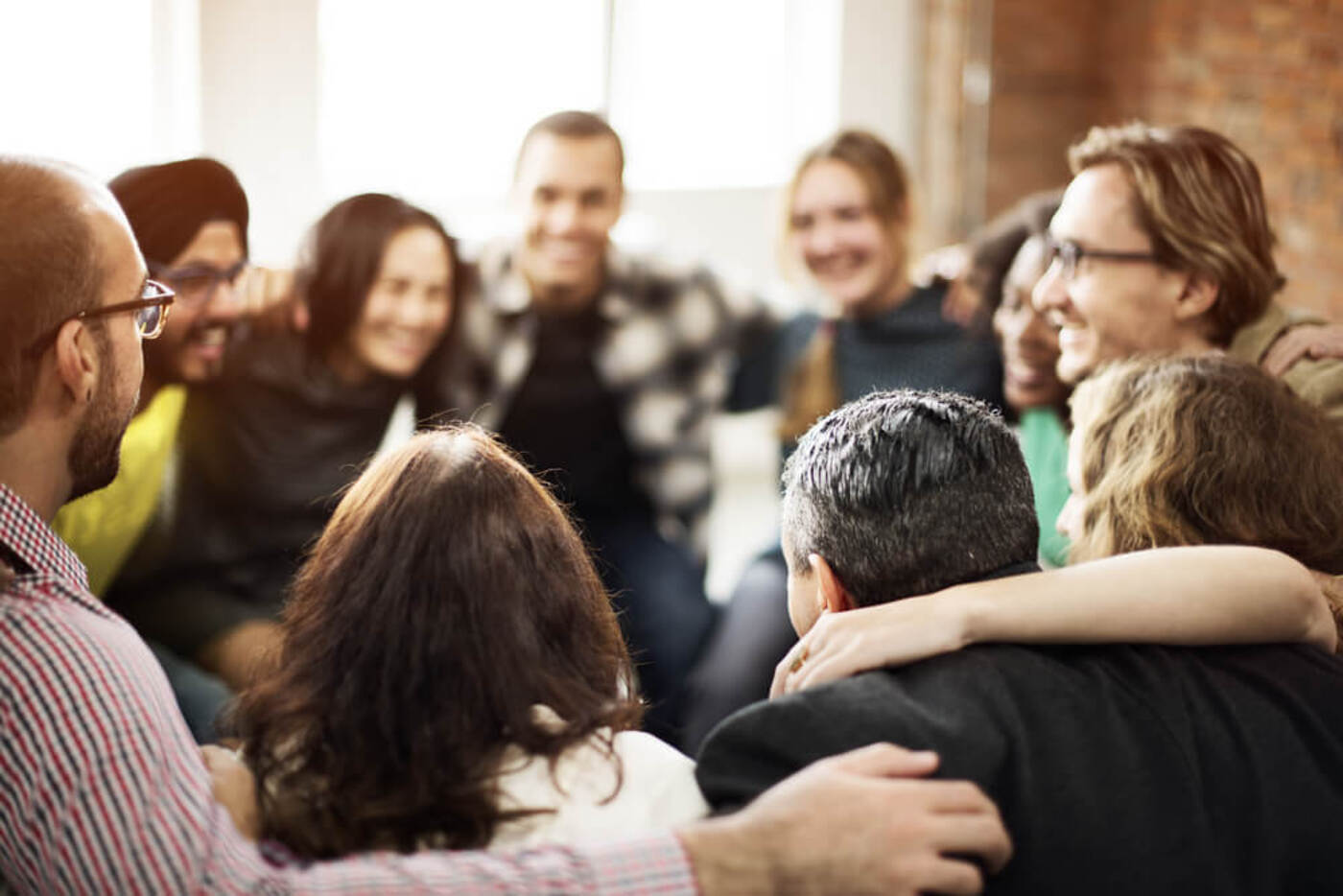 A group of people holding each other and standing in a circle together and smiling