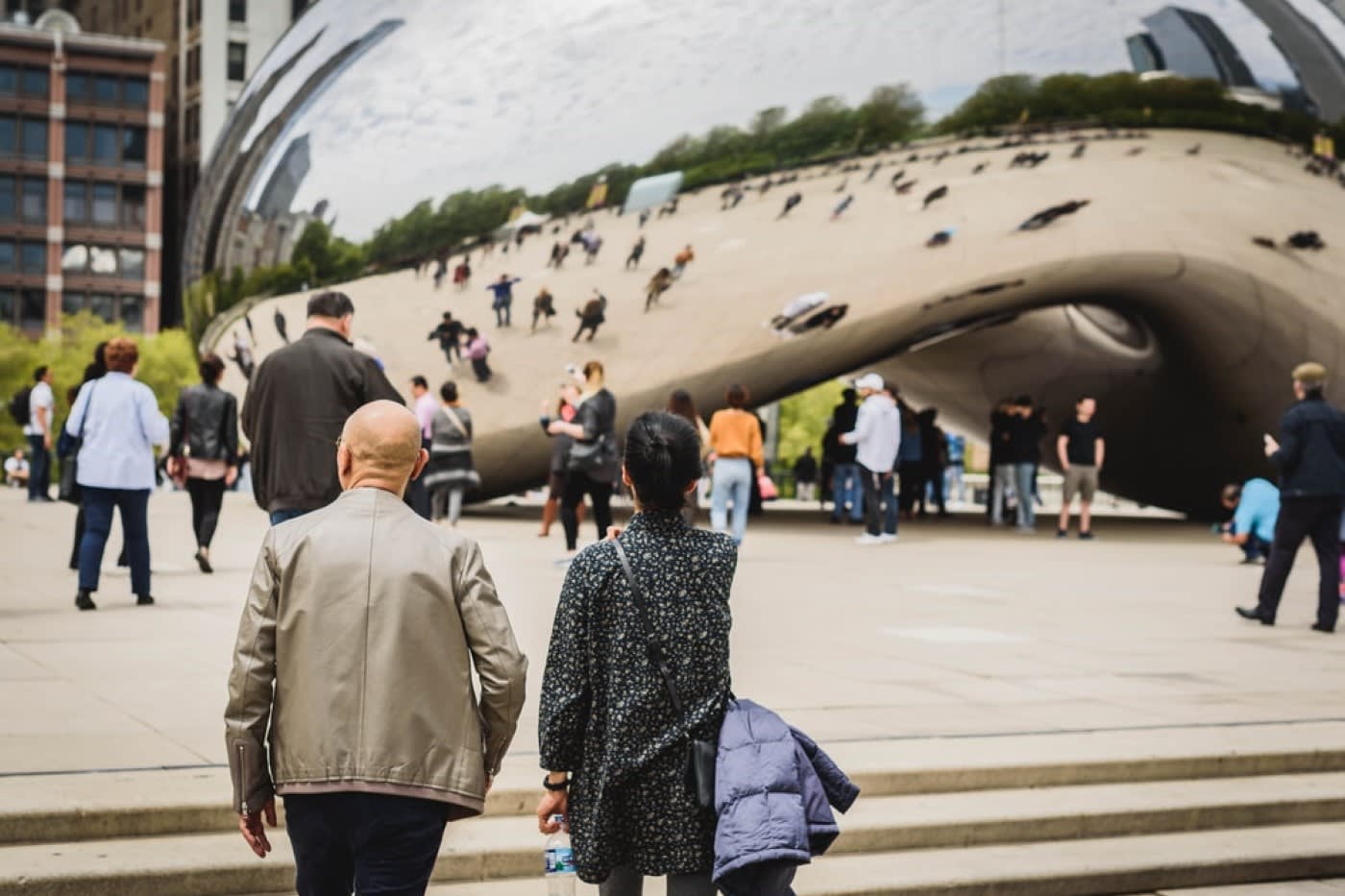 Tourists and locals standing around the Bean landmark in Chicago