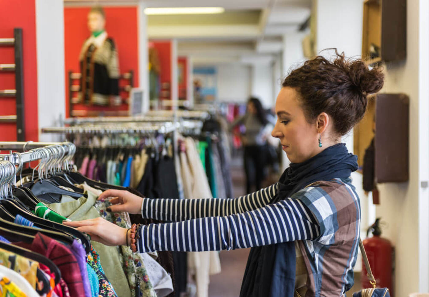 woman looking at clothing in a thrift store