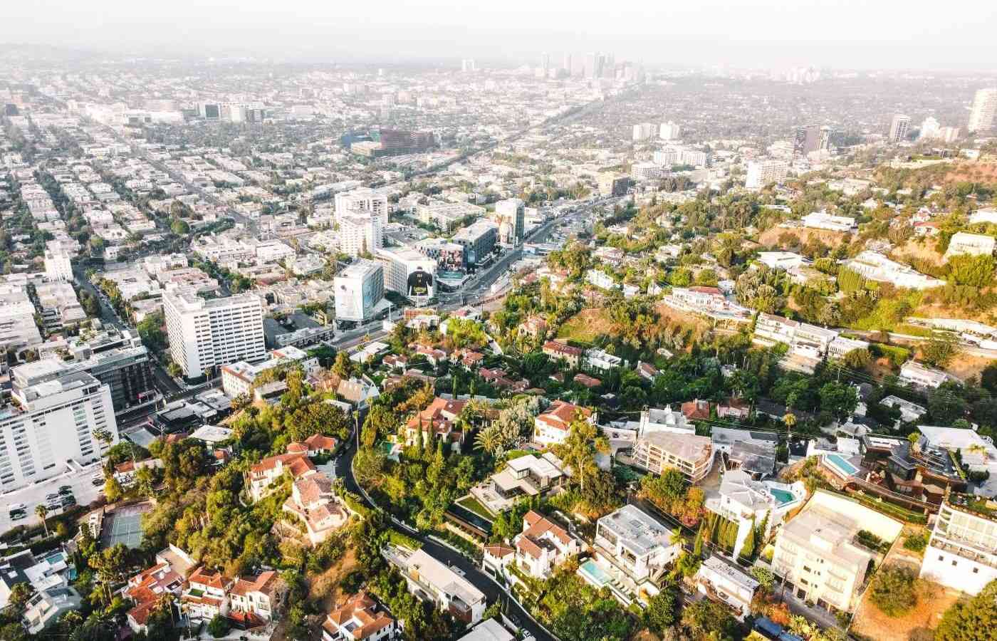 An aerial view of west hollywood with residential buildings in the top left and single family homes surrounded by greenery in the bottom right.