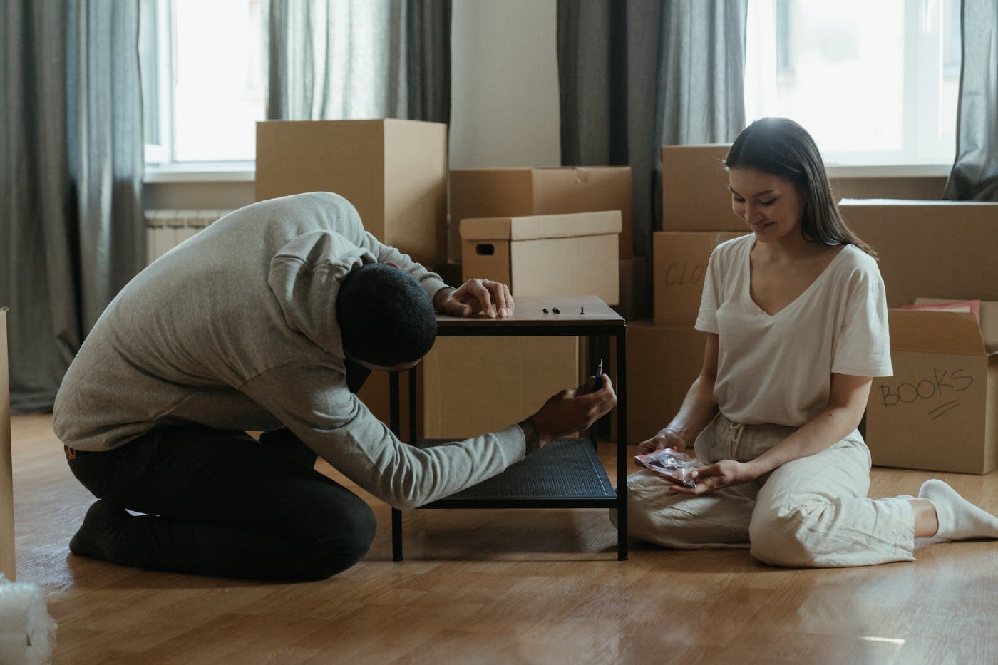 couple sitting in front of moving boxes, disassembling their coffee table