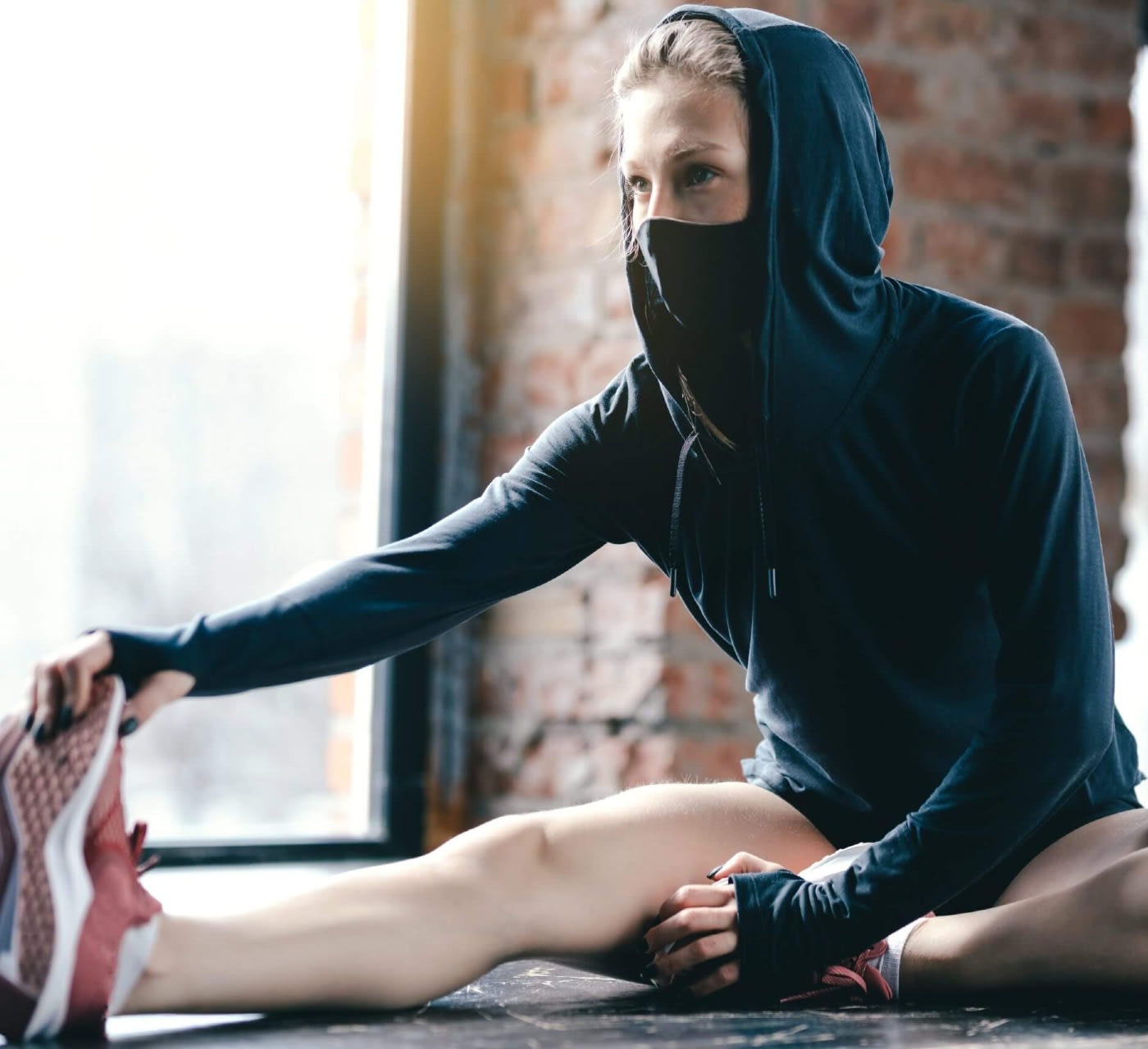 a girl, wearing a face mask stretching her leg on the floor
