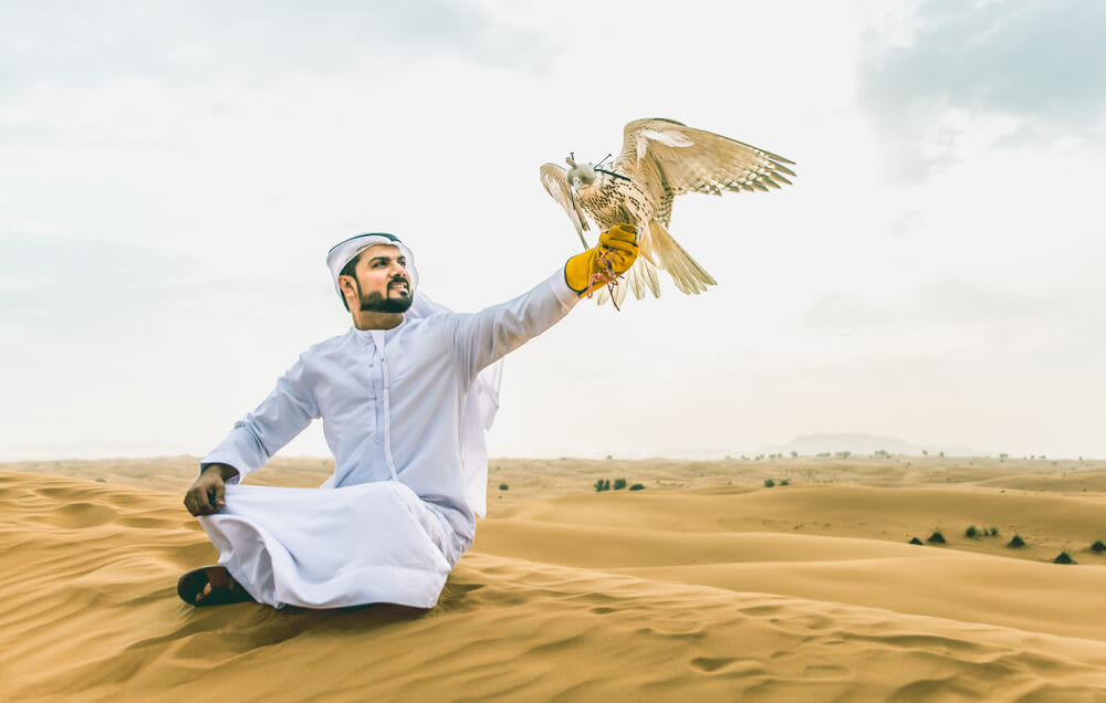 man holding a wild bird in the desert