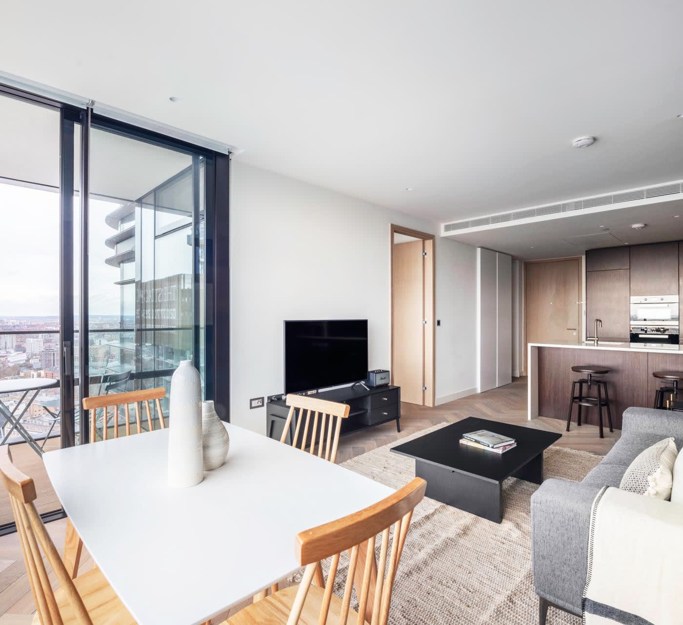 open-plan furnished apartment. Wooden cabinets, grey, white and black tones and a balcony with gorgeous city views