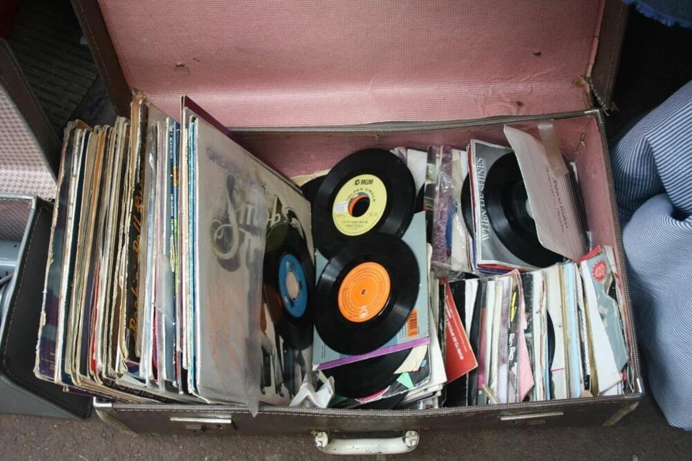 a black suitcase with pink interiors full of old and used records