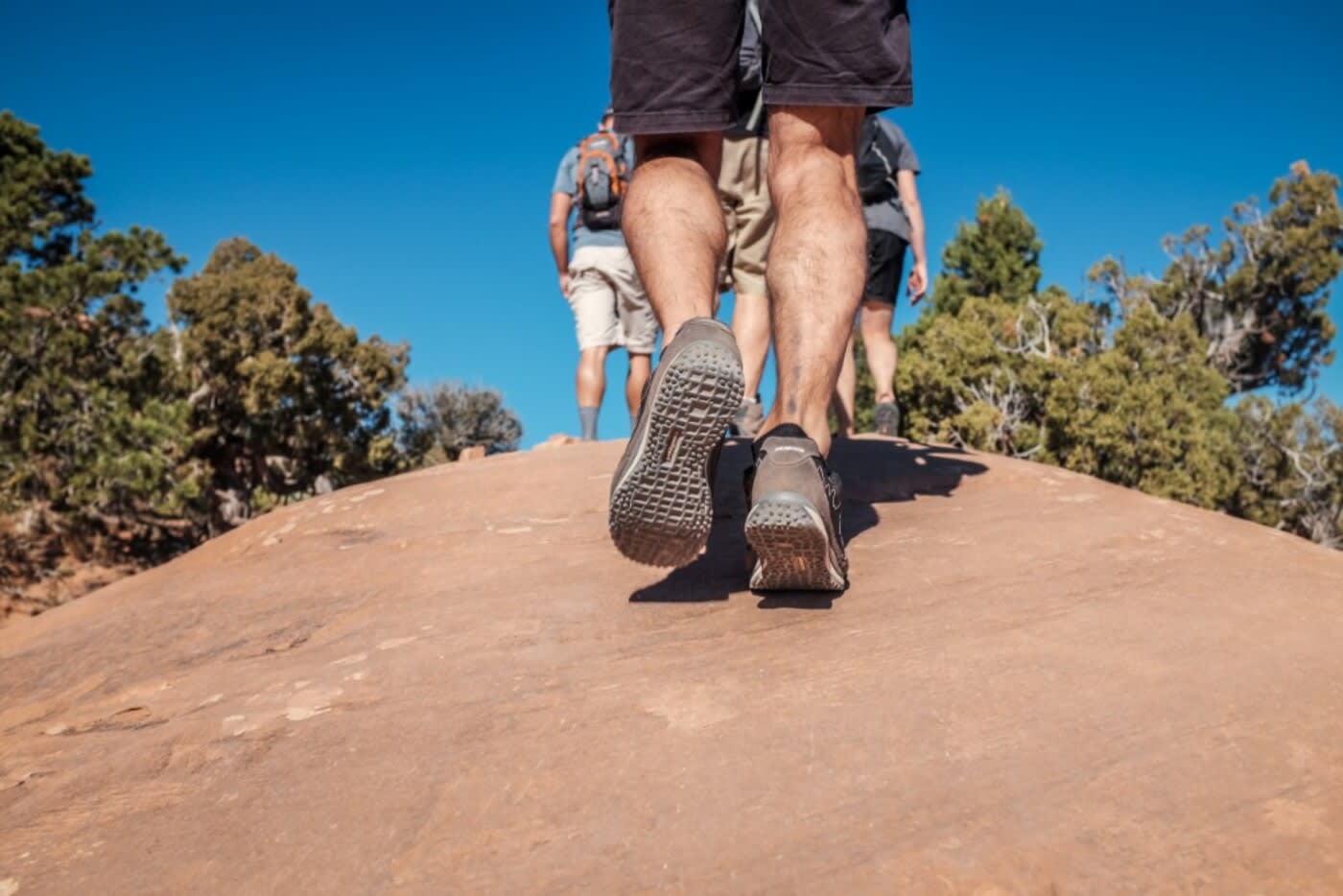 group of people going uphill, their feet are showing wearing shorts and traction shoes