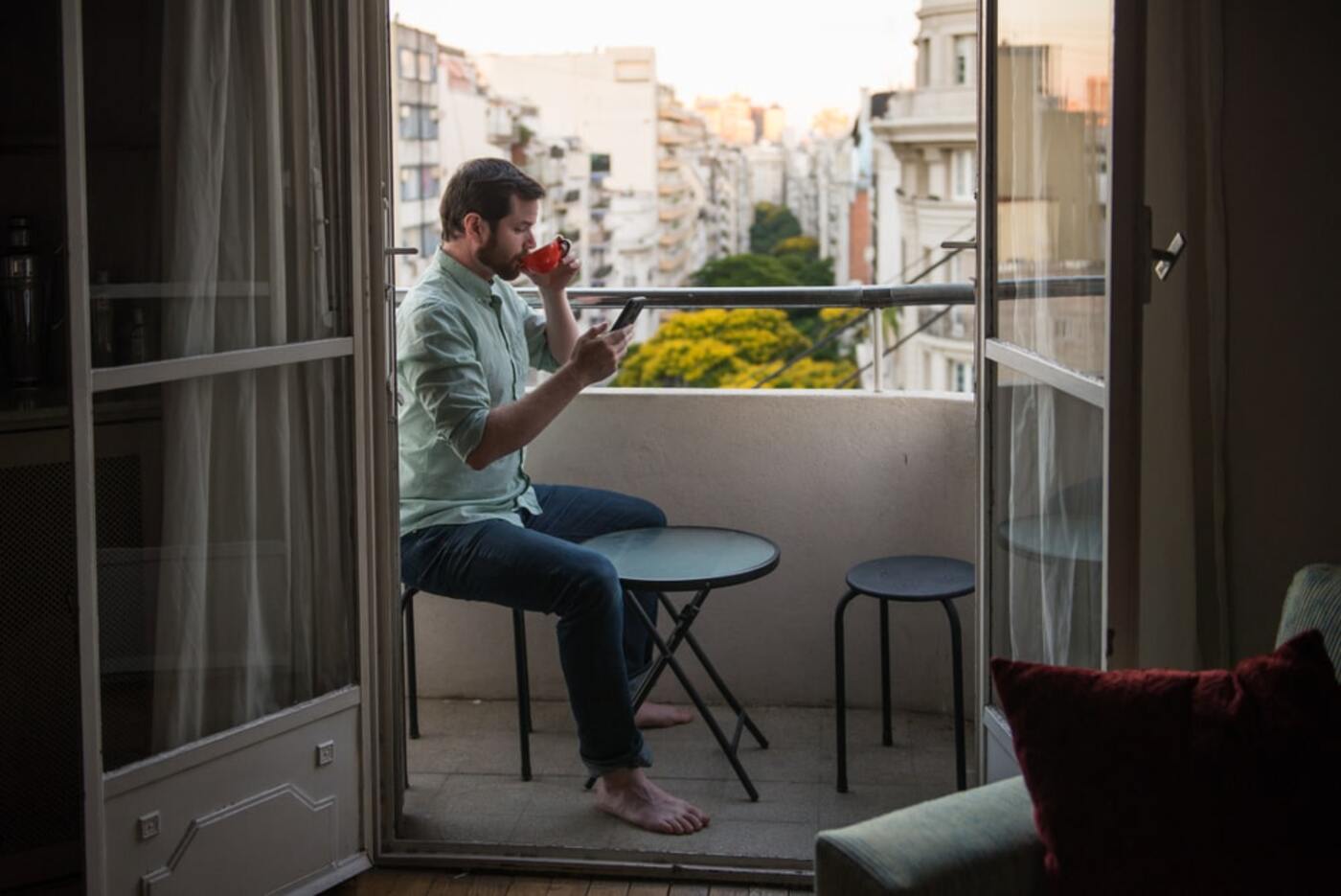 temporary housing man with beard reading phone and drinking coffee on terrace