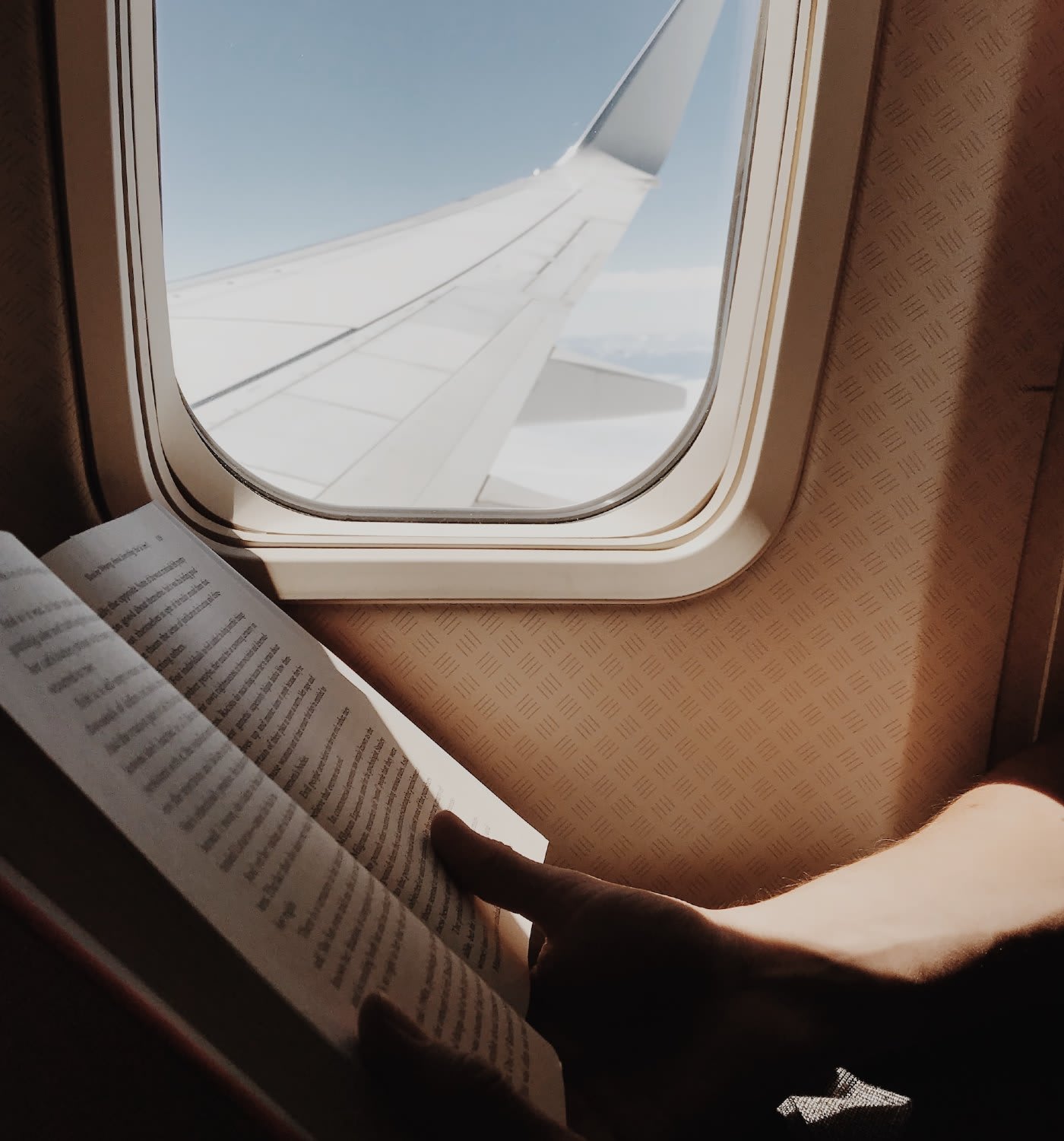 A person reading a book on an airplane flight.