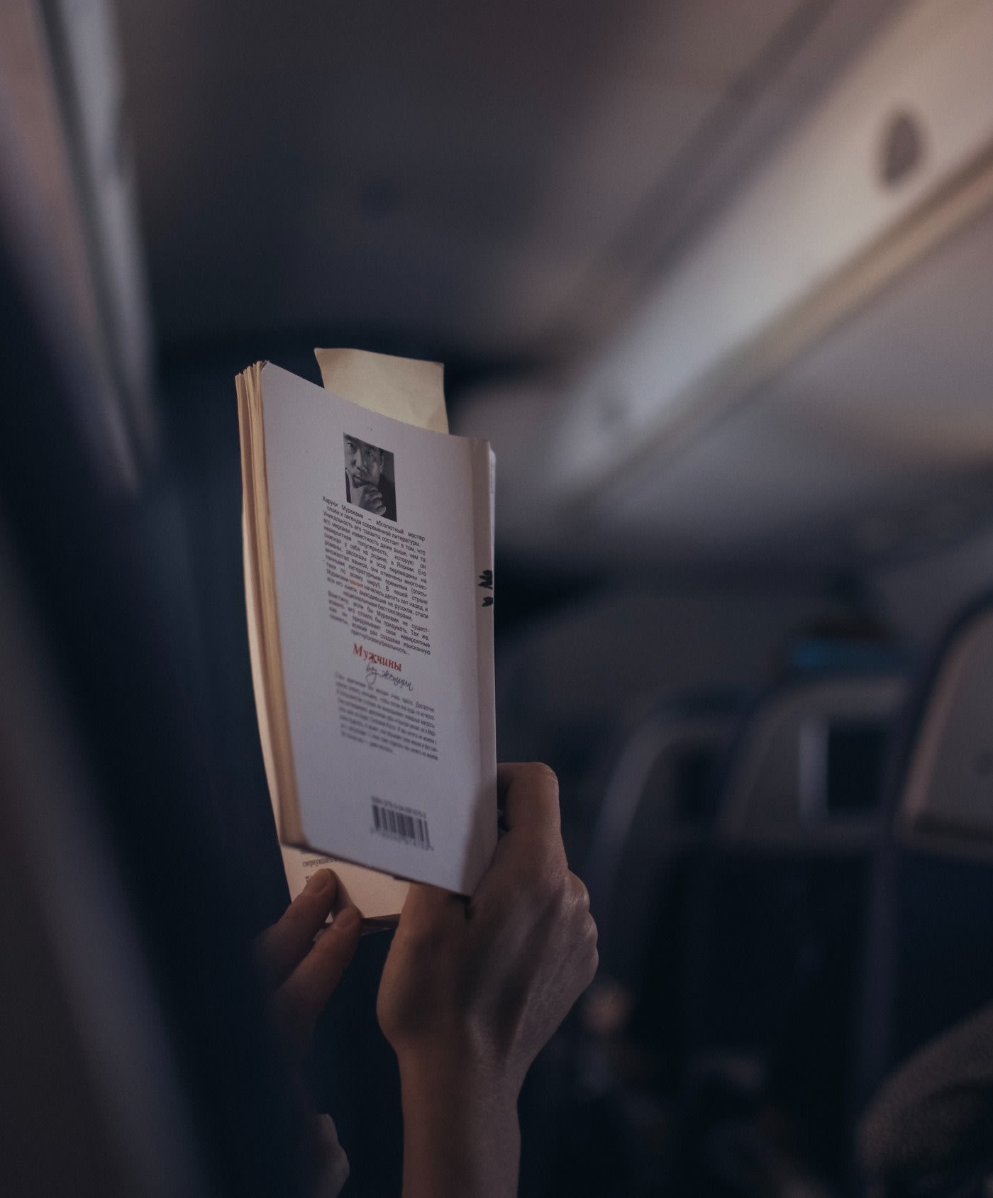 person sitting on aisle seat in an airplane is reading a book
