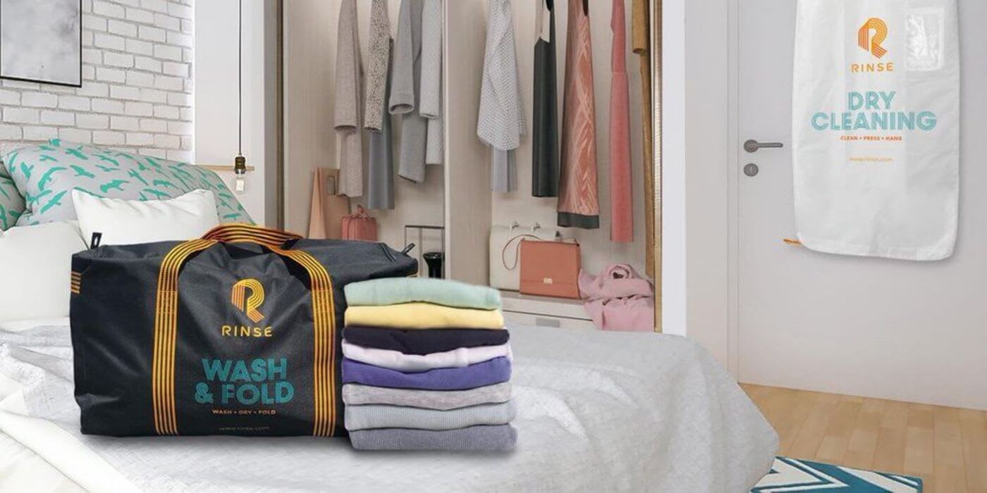 rinse duffel bag next to a stack of clean clothes on a bed