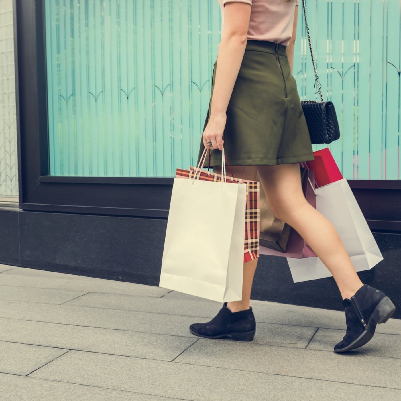 woman holding bags walking on the sidewalks
