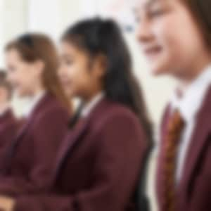 children wearing school uniforms, sitting in front of computers