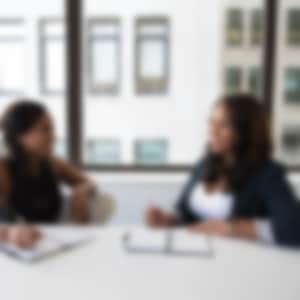 two women sit at a table and take notes