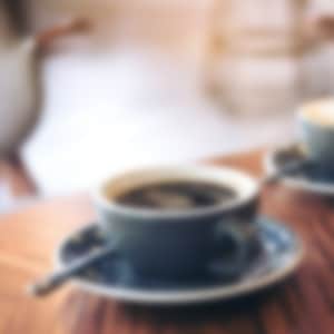 2 cups of coffee in blue mugs sitting on a wooden table