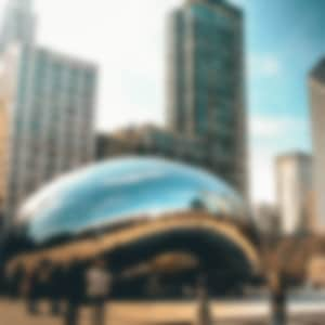 The giant "bean" statue in downtown Chicago with skyscrapers in the distance.