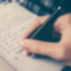 hand holding a pen writing a checklist in a journal