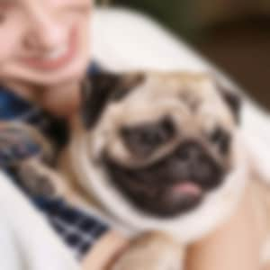 woman hugging pug while smiling