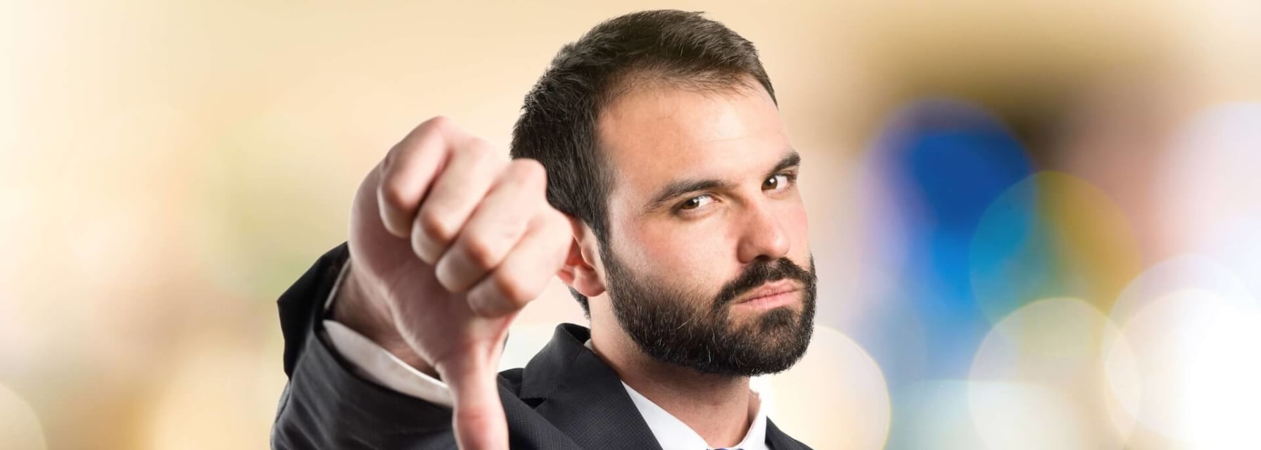 Man in suit with thumb pointing down