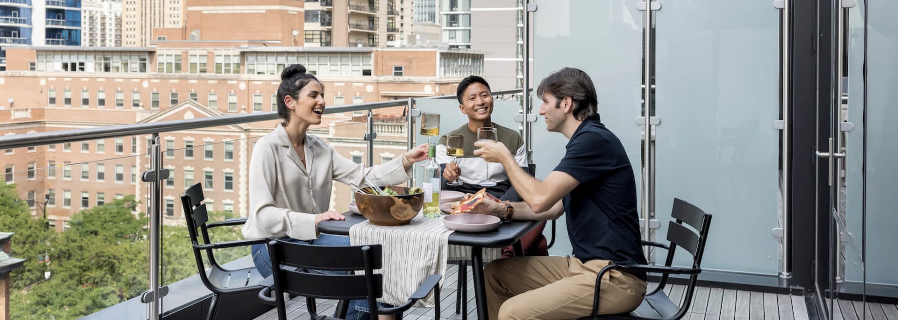 three friends enjoy a meal on a balcony