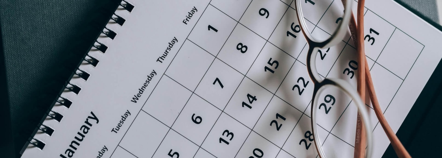 Monthly calendar with glasses on top of it