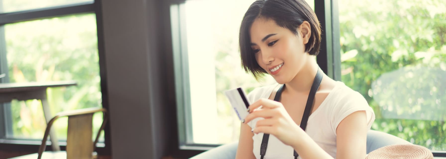 woman holding a credit card to make a payment on her laptop