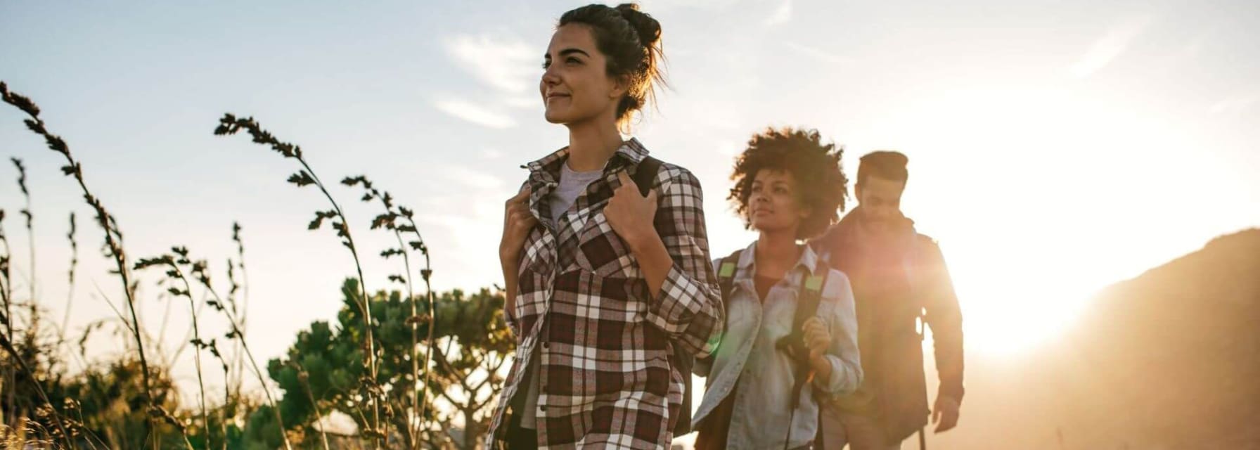 group of friends hiking along a green path on a sunny evening