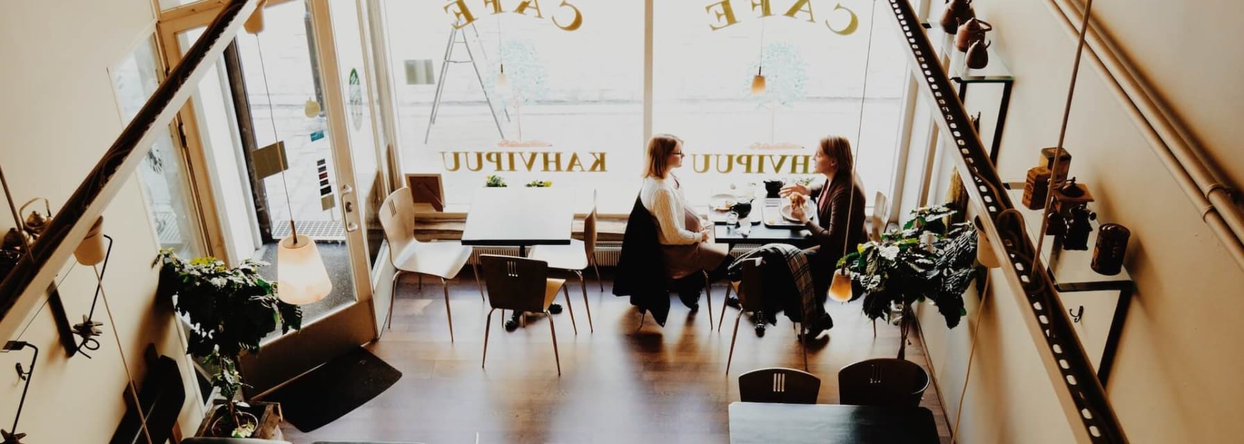 two women sit in a cafe talking and drinking