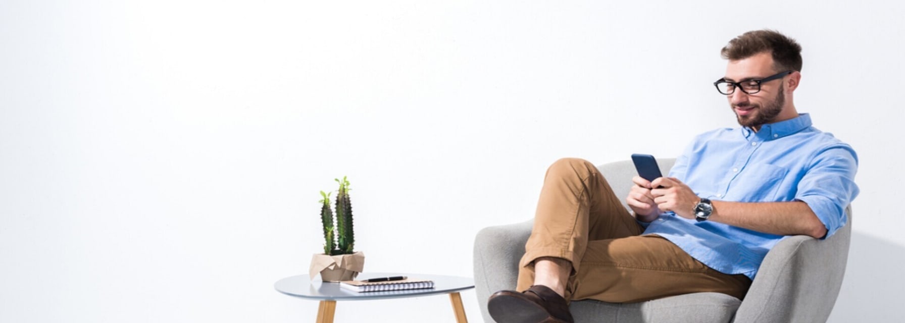 a man is sitting on an armchair looking at his phone