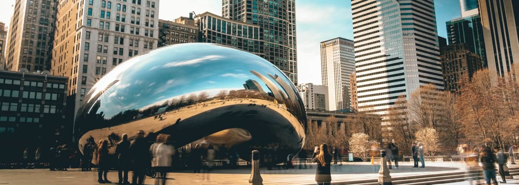 The giant "bean" statue in downtown Chicago with skyscrapers in the distance.