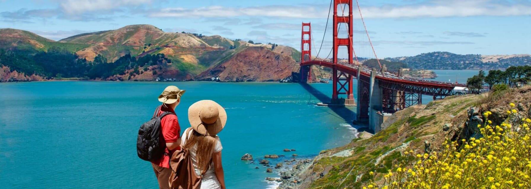 man and woman standing on a trail overlooking the SF Bay and Golden Gate Bridge