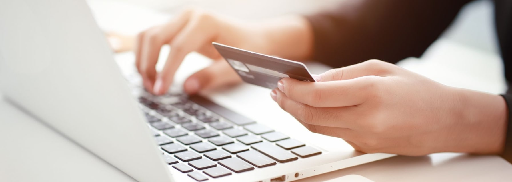 woman holding credit card implying online payment with white laptop