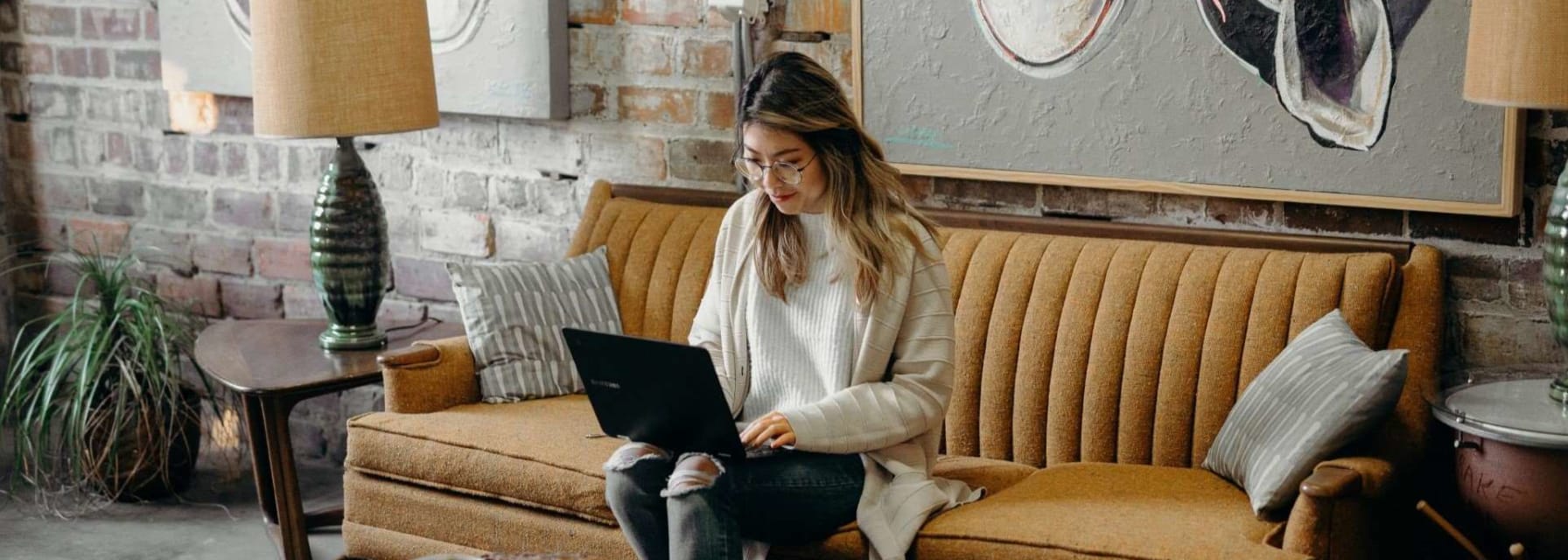 A woman sitting in her living room couch working on her laptop.