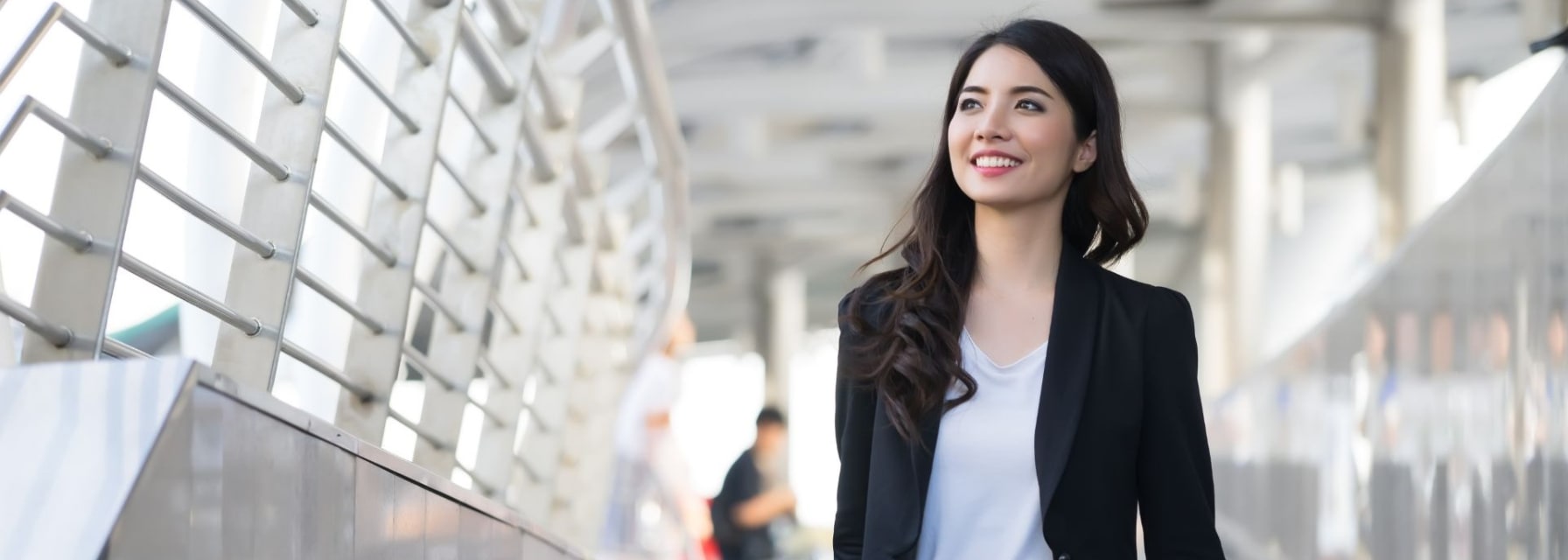 business travel - young woman with hand luggage walking down sidewalk in urban city