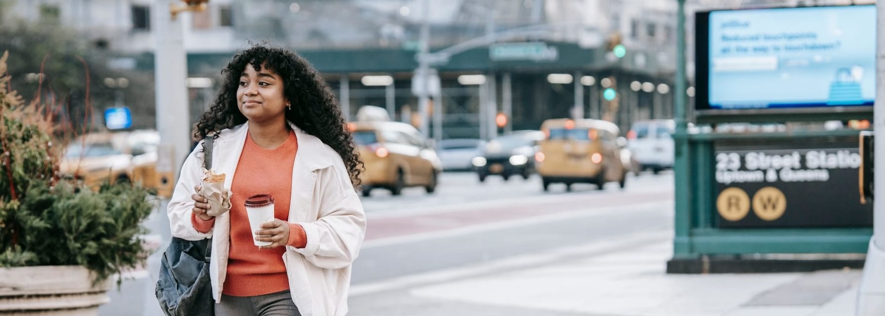 young woman walking in new york city with coffee
