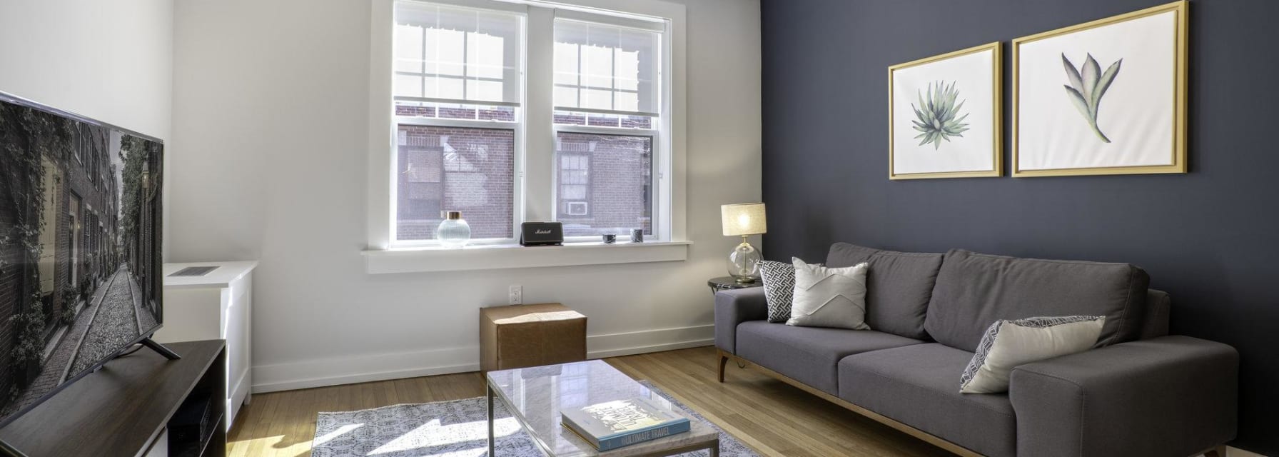 furnished apartment living room with a dark grey accent wall a marble coffee table and a TV