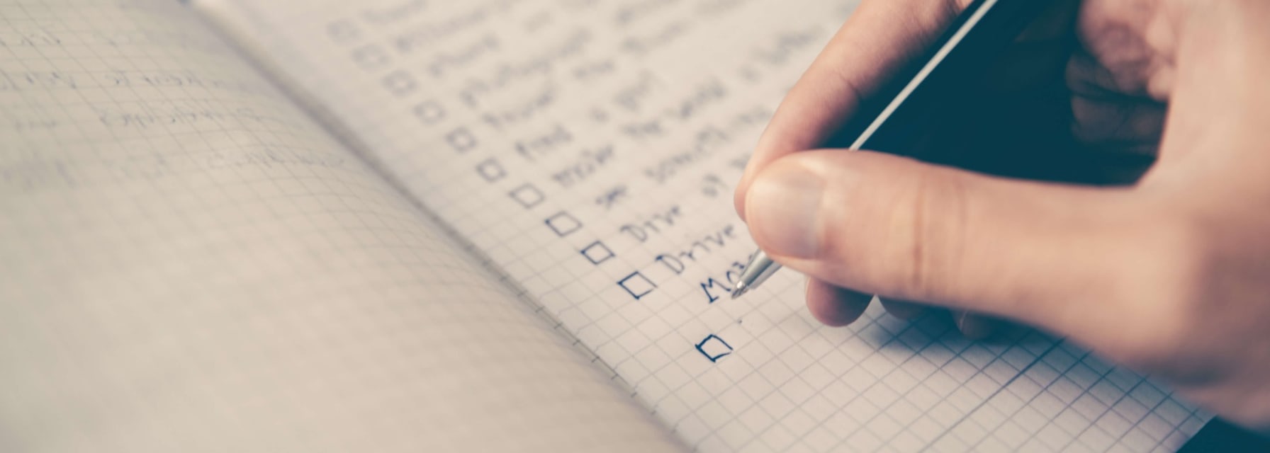 hand holding a pen writing a checklist in a journal