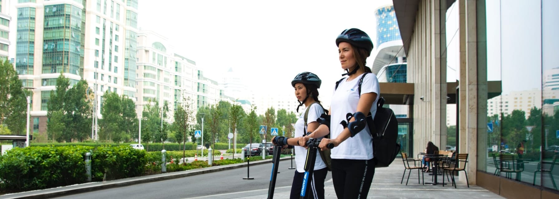 Two women riding electric scooters