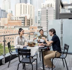 three friends enjoy a meal on a balcony